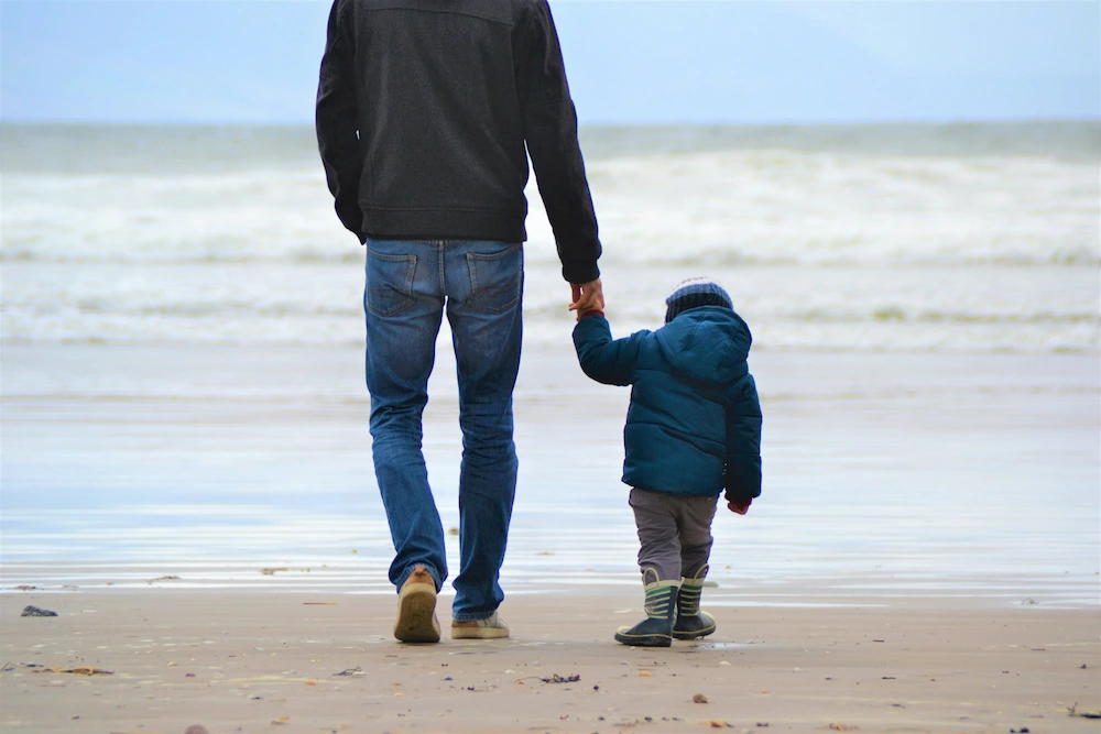 Padre paseando con su hijo de la mano disfrutando del régimen de custodia compartida.